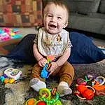 Smile, Photograph, Facial Expression, Green, Toy, Yellow, Baby, Happy, Fun, Toddler, People, Leisure, Child, Couch, Baby & Toddler Clothing, Event, Baby Playing With Toys, Play, Sitting, Person