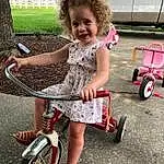 Wheel, Tire, Bicycle, Smile, Bicycle Tire, Dress, Pink, Grass, Vehicle, Toddler, Bicycle Frame, Summer, Automotive Tire, Bicycle Wheel, Bicycle Handlebar, Automotive Wheel System, Recreation, Fun, Person, Joy