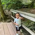 Smile, Plant, Shorts, Wood, Grass, People In Nature, Terrestrial Plant, Leisure, Happy, Tree, Fence, Toddler, Walkway, Forest, Hardwood, Wood Stain, Child, Person, Joy