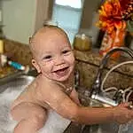 Smile, Tap, Plumbing Fixture, Tire, Water, Plant, Happy, Bicycle Tire, Bicycle Handlebar, Bathing, Leisure, Wheel, Chest, Plumbing, Toddler, Bicycle Wheel, Fun, Bicycle Saddle, Child, Barechested, Person, Joy