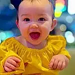 Cheek, Skin, Smile, Hand, Eyes, Orange, Happy, Baby & Toddler Clothing, Finger, Gesture, Yellow, Baby, Baby Laughing, Leisure, Toddler, Fun, Child, T-shirt, Baby Products, Sitting, Person