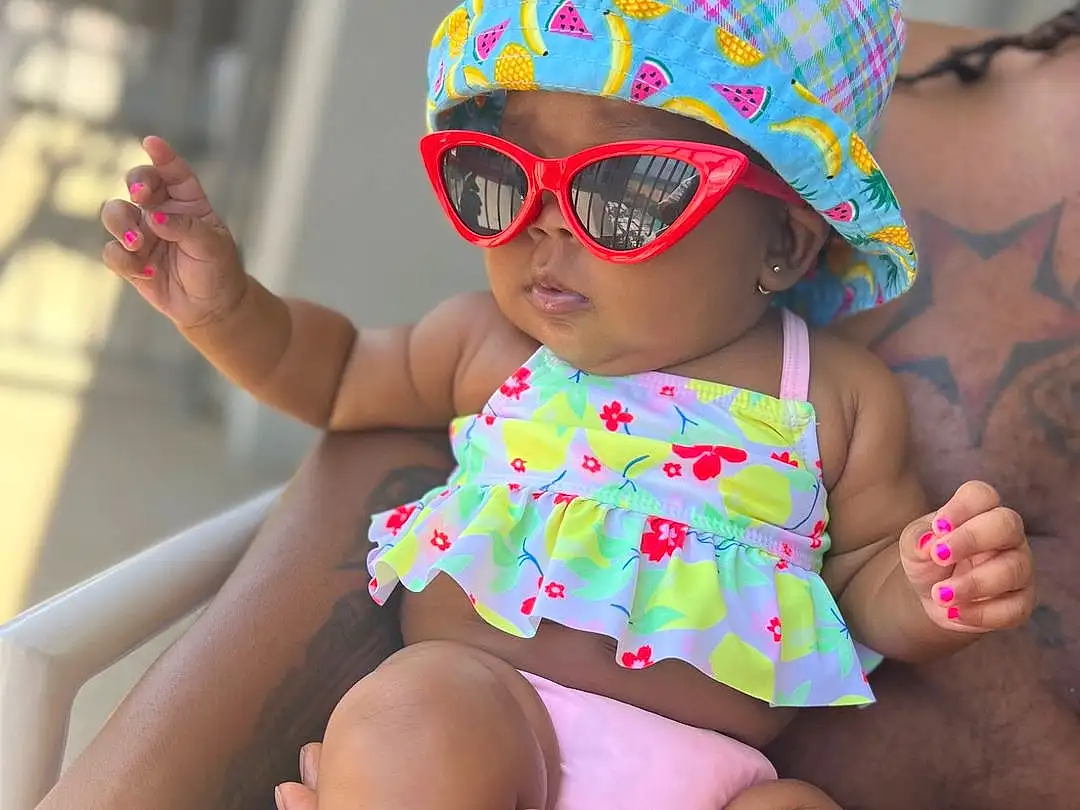 Glasses, Skin, Hand, Arm, Shoulder, Goggles, Hat, Dress, Leg, Sunglasses, Plant, Sun Hat, Human Body, Fashion, Baby & Toddler Clothing, Happy, Thigh, Eyewear, Pink, Yellow, Person