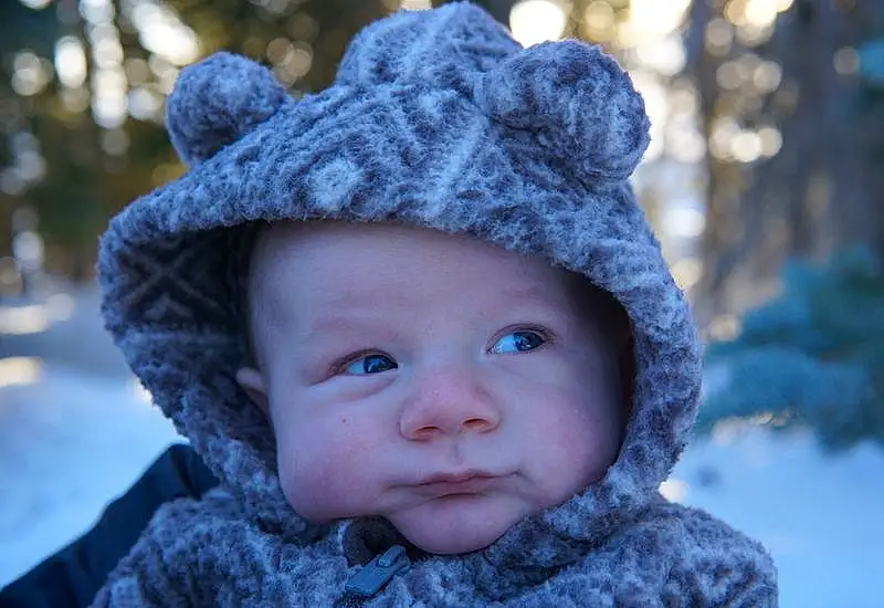 Clothing, Nose, Skin, Lip, Chin, Outerwear, Cap, Plant, Human Body, Snow, Flash Photography, Baby, Hat, Iris, Happy, Headgear, Tree, Freezing, Toddler, Person, Headwear