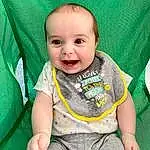 Child, Face, Facial Expression, Green, Toddler, Baby, Skin, Head, Baby & Toddler Clothing, T-shirt, Nose, Cheek, Yellow, Baby Products, Smile, Eyes, Sleeve, Sitting, Top, Person