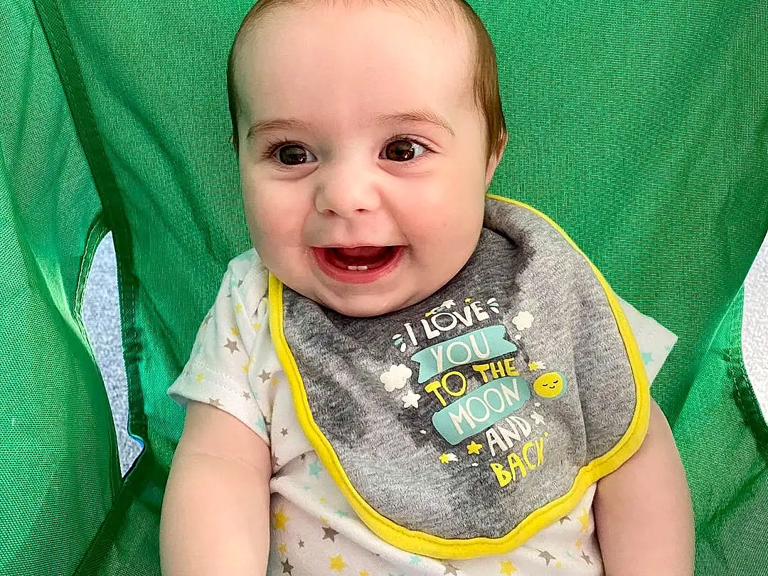 Child, Face, Facial Expression, Green, Toddler, Baby, Skin, Head, Baby & Toddler Clothing, T-shirt, Nose, Cheek, Yellow, Baby Products, Smile, Eyes, Sleeve, Sitting, Top, Person