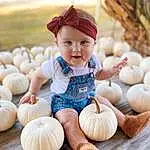 Clothing, Face, Hand, Eyes, Leg, Smile, Plant, Pumpkin, Human Body, Wood, Dress, People In Nature, Orange, Happy, Winter Squash, Calabaza, Headgear, Shorts, Squash, Natural Foods, Person