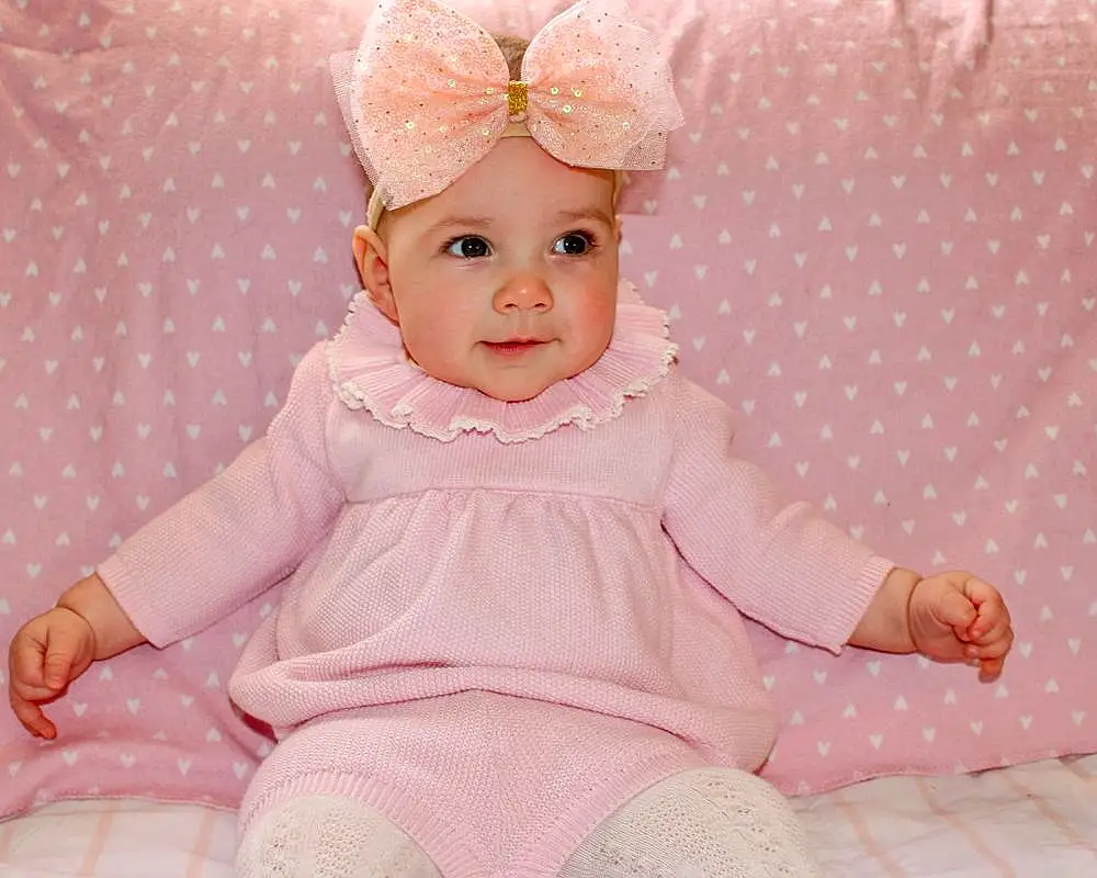 Skin, White, Baby & Toddler Clothing, Dress, Sleeve, Pink, Baby, Toddler, Happy, Pattern, Embellishment, Magenta, Comfort, Fashion Accessory, Child, Peach, Headpiece, Headband, Sitting, Costume Hat, Person, Headwear