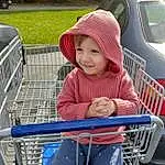 Tire, Plant, Vehicle, Car, Shopping Cart, Toddler, Smile, Public Space, Leisure, Grass, Fun, Baby & Toddler Clothing, Automotive Tire, Wheel, Recreation, Child, Electric Blue, Vroom Vroom, Sitting, Tree, Person, Joy, Headwear