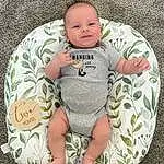 Face, Cheek, Skin, Head, Hand, Arm, Eyes, Smile, Leg, Comfort, Baby & Toddler Clothing, Textile, Baby, Sleeve, Toddler, Grass, Headgear, T-shirt, Pattern, Linens, Person
