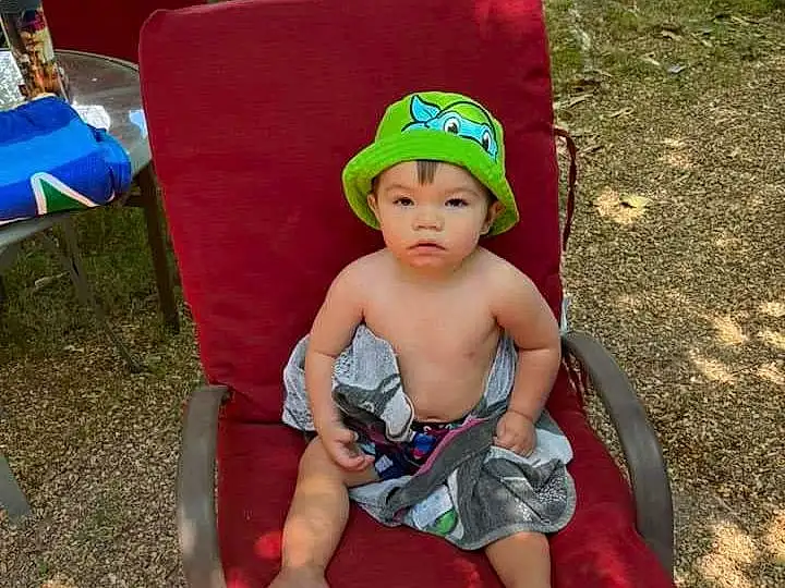 Blue, Chair, Toddler, Hat, Baby & Toddler Clothing, Leisure, Outdoor Furniture, Baby, Cap, Grass, Fun, Recreation, Child, Thigh, Lap, Sun Hat, Shorts, Event, Sitting, Human Leg, Person, Headwear