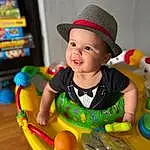 Skin, Smile, Baby Playing With Toys, Facial Expression, Baby, Happy, Toy, Hat, Toddler, Sun Hat, Fun, Child, Cap, Baby & Toddler Clothing, Leisure, Baby Products, Recreation, Riding Toy, Room, Baby Toys, Person, Joy, Headwear