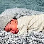 Skin, White, Comfort, Textile, Grey, Grass, Baby, Linens, Toddler, Wool, Bedding, Furry friends, Winter, Bedtime, Happy, Nap, Room, Wood, Person, Headwear
