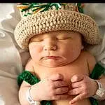 Skin, Head, Lip, Hand, Eyes, Smile, Mouth, Human Body, Cap, Happy, Gesture, Thumb, Comfort, Finger, Baby, Toddler, Headgear, Hat, Nail, Baby Sleeping, Person, Headwear