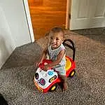 Head, Toy, Riding Toy, Baby, Toddler, Automotive Design, Wood, Comfort, Door, Hardwood, Recreation, Room, Sitting, Grass, Toy Vehicle, Child, Fun, Carmine, Person, Joy