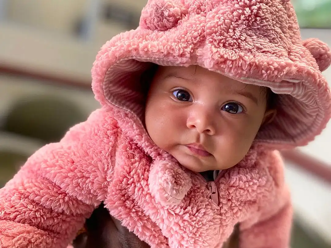Face, Nose, Cheek, Skin, Head, Lip, Chin, Outerwear, Eyes, Facial Expression, Hat, Mouth, Cap, Sun Hat, Human Body, Textile, Sleeve, Happy, Baby, Pink, Person, Headwear