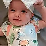 Face, Cheek, Skin, Head, Lip, Chin, Outerwear, Hairstyle, Smile, Facial Expression, White, Baby & Toddler Clothing, Dress, Sleeve, Cap, Baby, Yellow, Pink, Toddler, Person, Headwear