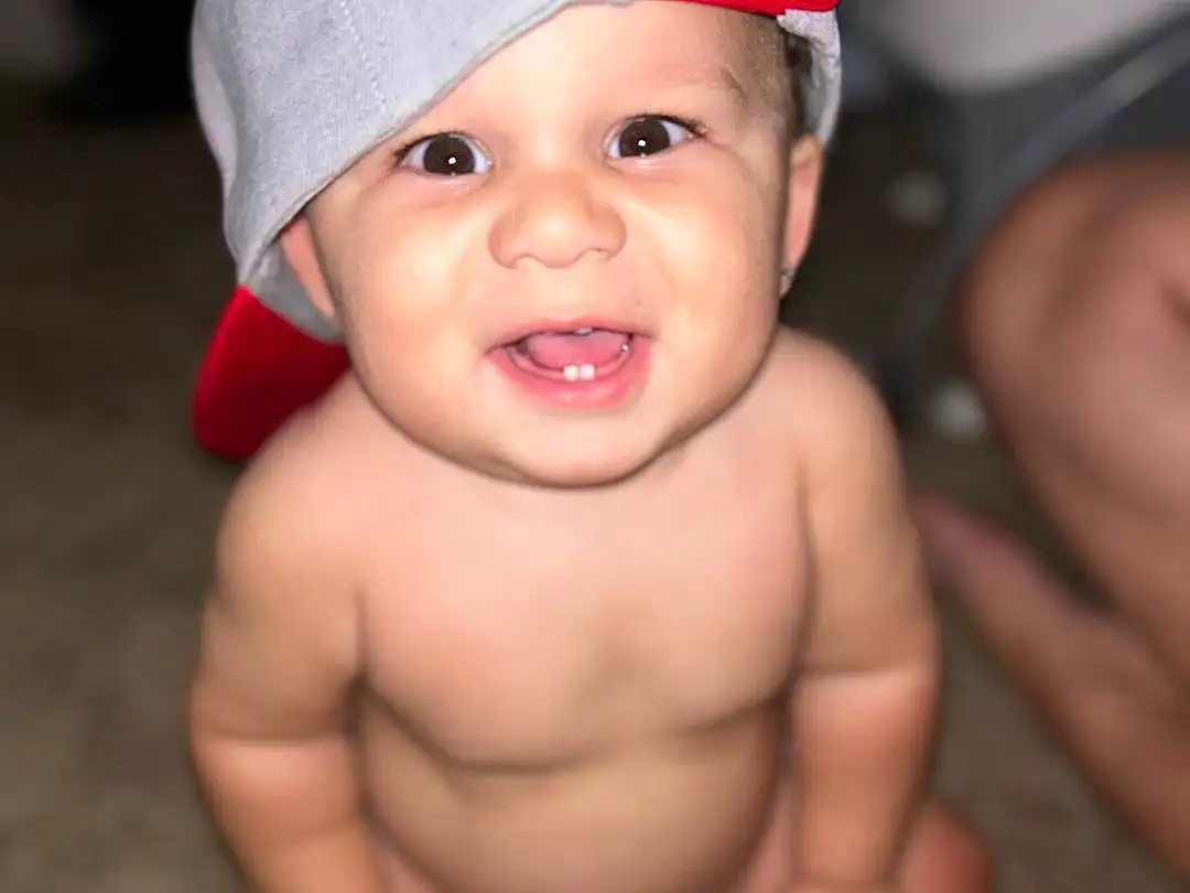 Skin, Lip, Eyes, Eyebrow, Smile, Cap, Mouth, Human Body, Happy, Baby, Baseball Cap, Finger, Toddler, Costume Hat, Fun, Thumb, Child, Fashion Accessory, Foot, Chest, Person, Headwear