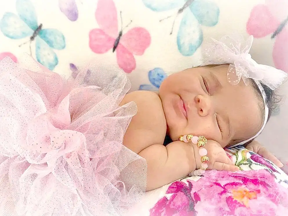 Textile, Pink, Petal, Happy, Eyelash, Magenta, Pattern, Headpiece, Fashion Accessory, Baby, Headband, Peach, Embellishment, Hair Accessory, Linens, Toddler, Baby Sleeping, Baby & Toddler Clothing, Sweetness, Portrait Photography, Person