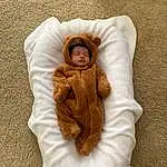 Clothing, Face, Skin, Outerwear, Comfort, Baby Sleeping, Sleeve, Textile, Baby, Baby & Toddler Clothing, Headgear, Beige, Toddler, Linens, Bedding, Furry friends, Baby Products, Sitting, Wool, Child, Person