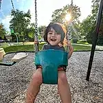 Smile, Sky, Plant, Cloud, Swing, Grass, Tree, Happy, People In Nature, Thigh, Leisure, Fun, Public Space, Playground, Outdoor Play Equipment, City, Recreation, Summer, Toddler, Shorts, Person, Joy