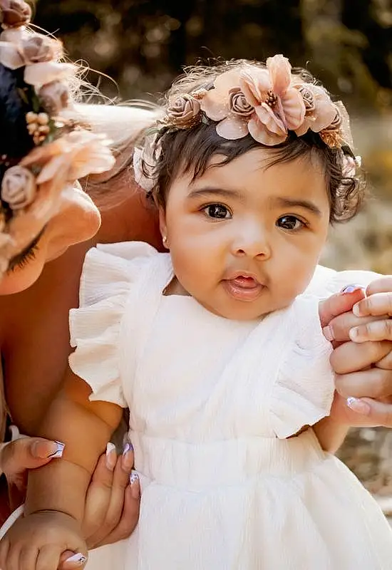 Face, Skin, Head, Hand, Hairstyle, Facial Expression, White, Dress, Flash Photography, Fashion, Happy, Flower, Petal, Textile, Baby, Gesture, Pink, Finger, Bridal Clothing, Baby & Toddler Clothing, Person, Headwear