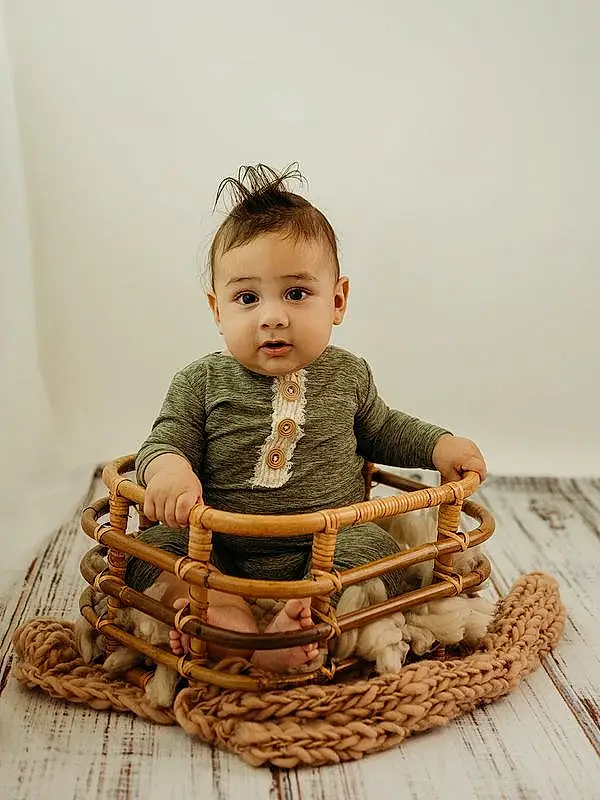 Outerwear, Arm, Doll, Sleeve, Wood, Baby & Toddler Clothing, Baby, Basket, Toddler, Storage Basket, Happy, Toy, Picnic Basket, Child, Sitting, Wicker, Fashion Accessory, Baby Products, Pattern, Person