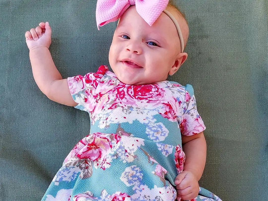 Face, Skin, Smile, Facial Expression, White, One-piece Garment, Baby & Toddler Clothing, Dress, Sleeve, Purple, Happy, Pink, Baby, Toddler, Day Dress, Sandal, Pattern, Magenta, Child, Foot, Person, Headwear