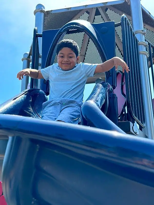 Shorts, Sky, Smile, Blue, Hat, Leisure, Chute, Electric Blue, T-shirt, Fun, Recreation, Toddler, Outdoor Play Equipment, City, Shade, Automotive Exterior, Vroom Vroom, Vacation, Amusement Park, Person, Joy