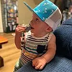 Skin, Cap, Baby & Toddler Clothing, Baby, Finger, Toddler, Hat, Baseball Cap, Wood, Sun Hat, Sitting, Fun, Child, Electric Blue, Fashion Accessory, Room, Happy, Leisure, Hardwood, Person, Headwear