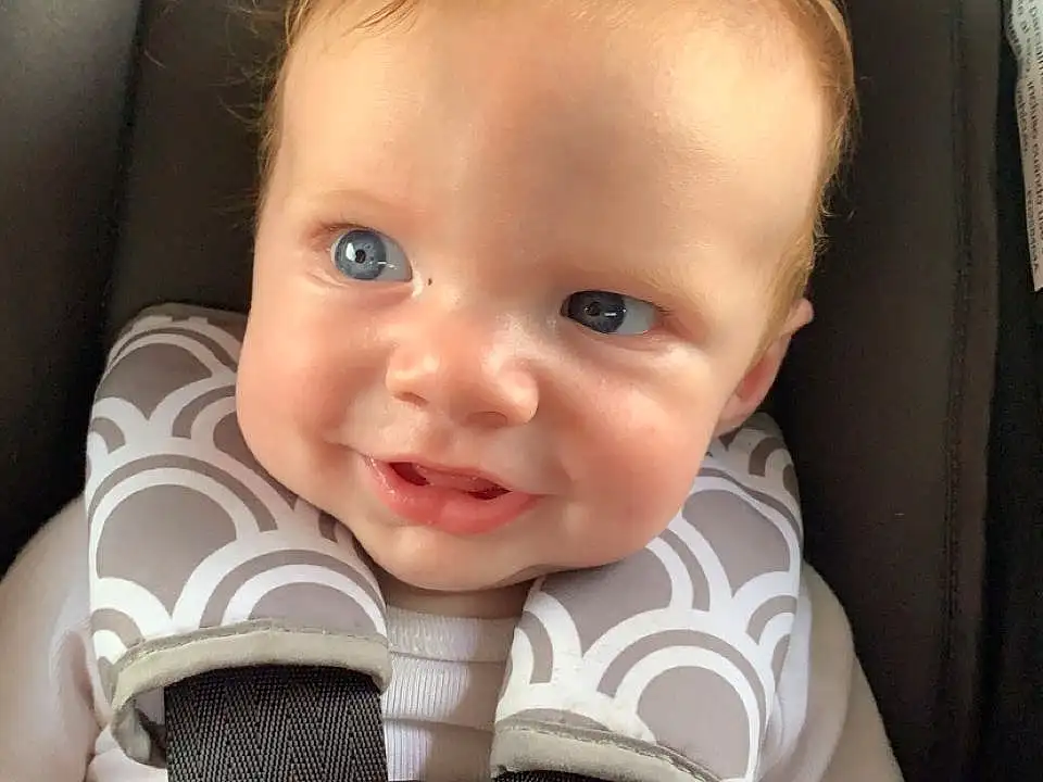 Face, Cheek, Skin, Smile, Eyebrow, Eyes, Comfort, Seat Belt, Iris, Baby, Automotive Design, Child, Toddler, Car Seat, Auto Part, Baby Carriage, Flash Photography, Blond, Baby & Toddler Clothing, Person