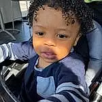 Hairstyle, Plant, Toddler, Black Hair, Happy, Child, Baby, Fun, Auto Part, Car Seat, Vroom Vroom, Afro, Comfort, Sitting, Steering Wheel, Chair, Luxury Vehicle, Baby Products, Automotive Tire, Tree