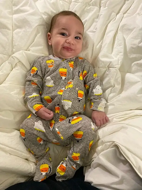 Face, Skin, Head, Smile, Facial Expression, Comfort, Baby & Toddler Clothing, Textile, Sleeve, Baby, Toddler, Linens, Child, Pattern, Baby Products, Sitting, Room, Play, Bedding, Person