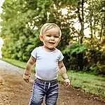 Plant, Hairstyle, Smile, Leg, People In Nature, Natural Environment, Flash Photography, Tree, Happy, Standing, Gesture, Sunlight, Grass, Toddler, Fun, Leisure, T-shirt, Child, Blond, Recreation, Person, Joy