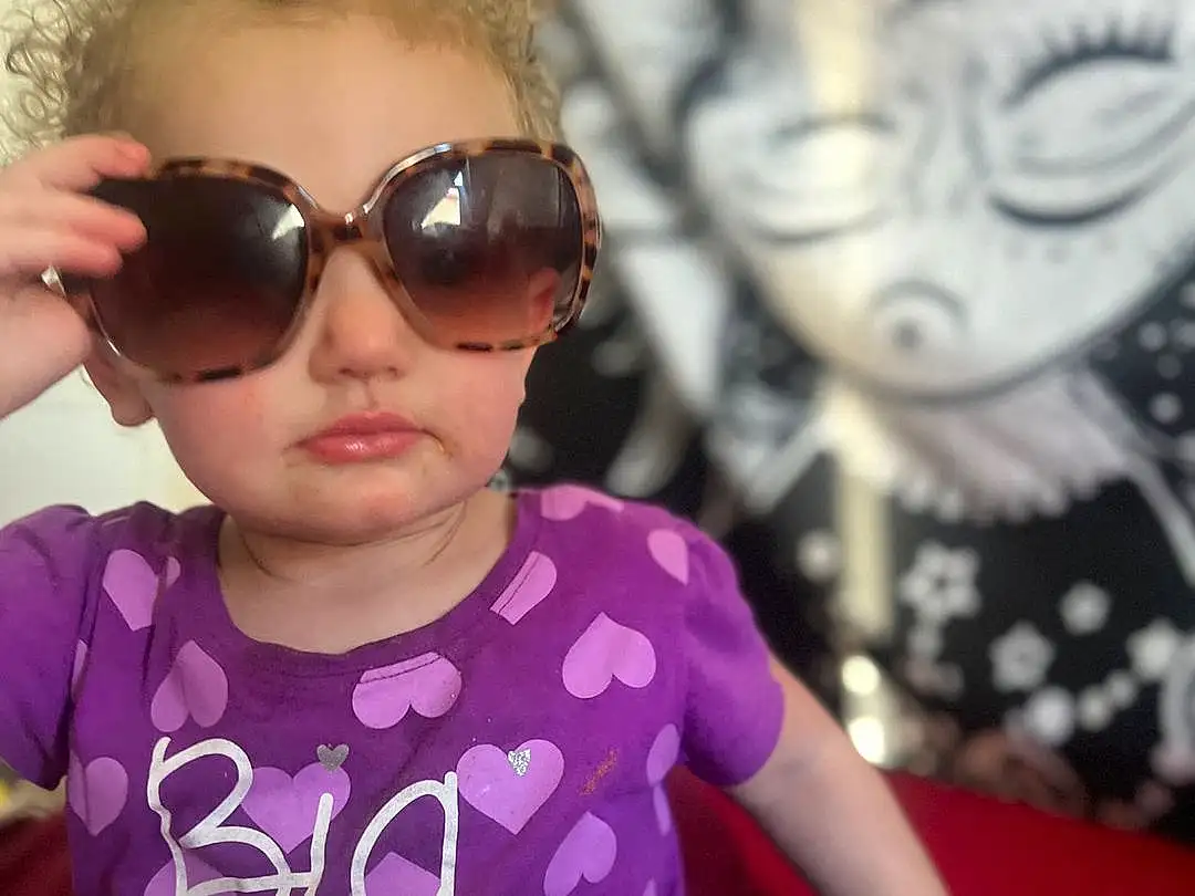 Glasses, Head, Lip, Outerwear, Hairstyle, Vision Care, Facial Expression, Sunglasses, Goggles, Purple, Fashion, Sleeve, Eyewear, Happy, Pink, Baby & Toddler Clothing, Cool, Fun, Toddler, Person