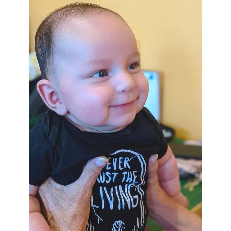 Nose, Smile, Head, Arm, Ear, Neck, Baby & Toddler Clothing, Sleeve, Happy, Gesture, T-shirt, Baby, Toddler, Thumb, Chest, Electric Blue, Sitting, Pattern, Child, Sportswear, Person, Joy
