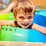 Smile, Water, Facial Expression, Happy, Leisure, Fun, Swimming Pool, Summer, Toddler, T-shirt, Grass, Recreation, Bathing, Personal Protective Equipment, Inflatable, Child, Play, Laugh, Surfboard, Vacation, Person, Joy
