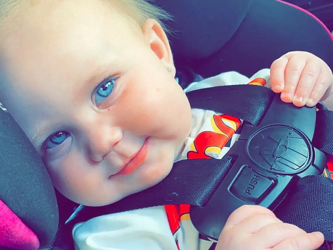 Skin, Eyes, Facial Expression, Smile, Blue, Azure, Steering Wheel, Steering Part, Happy, Baby & Toddler Clothing, Toddler, Cool, Car Seat, Automotive Design, Baby, Auto Part, Wheel, Grass, Person