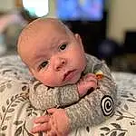 Cheek, Skin, Human Body, Sleeve, Baby, Gesture, Comfort, Baby & Toddler Clothing, Happy, Toddler, Television, Child, Linens, Room, Sitting, Fun, Furry friends, Pattern, Portrait Photography, Person