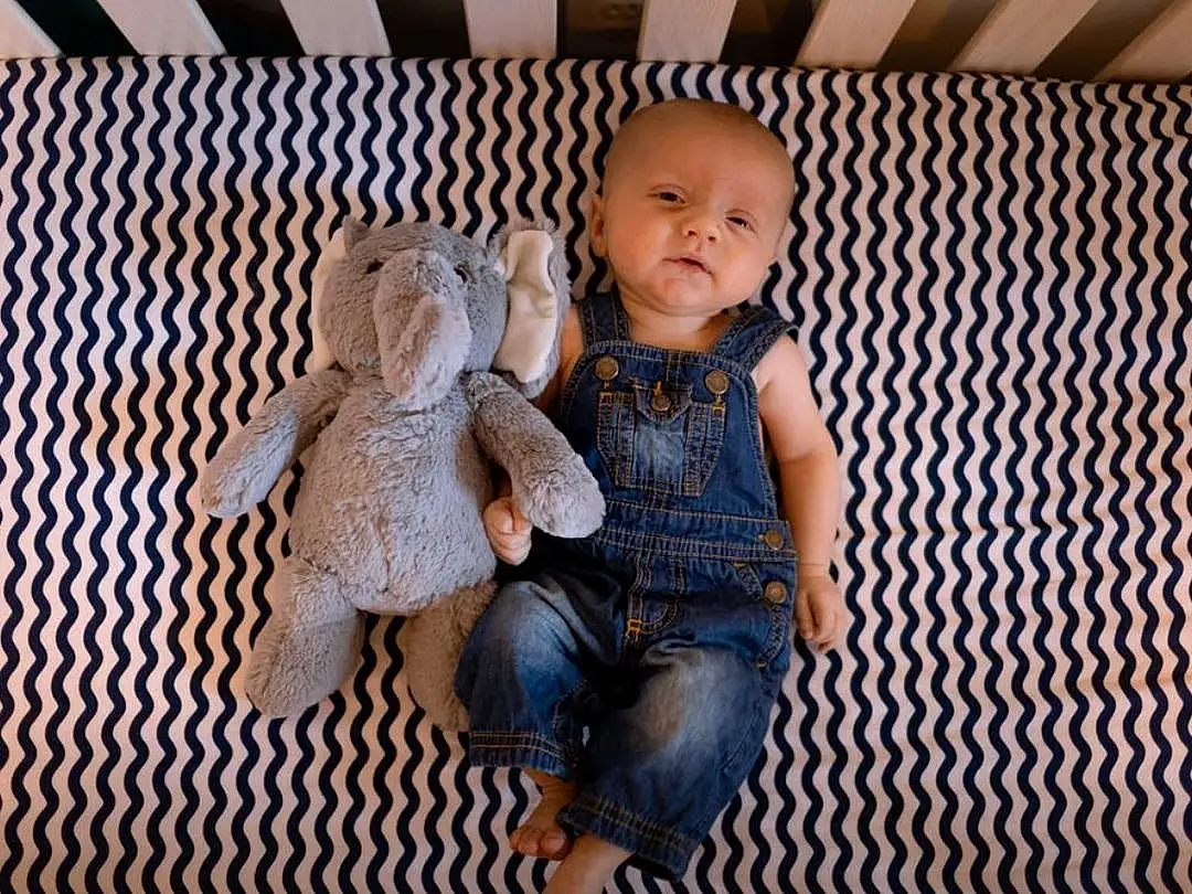 Clothing, Cheek, Skin, Head, Toy, Doll, Wood, Textile, Sleeve, Smile, Comfort, Baby & Toddler Clothing, Fawn, Happy, Toddler, Pattern, Foot, Sitting, Denim, Person