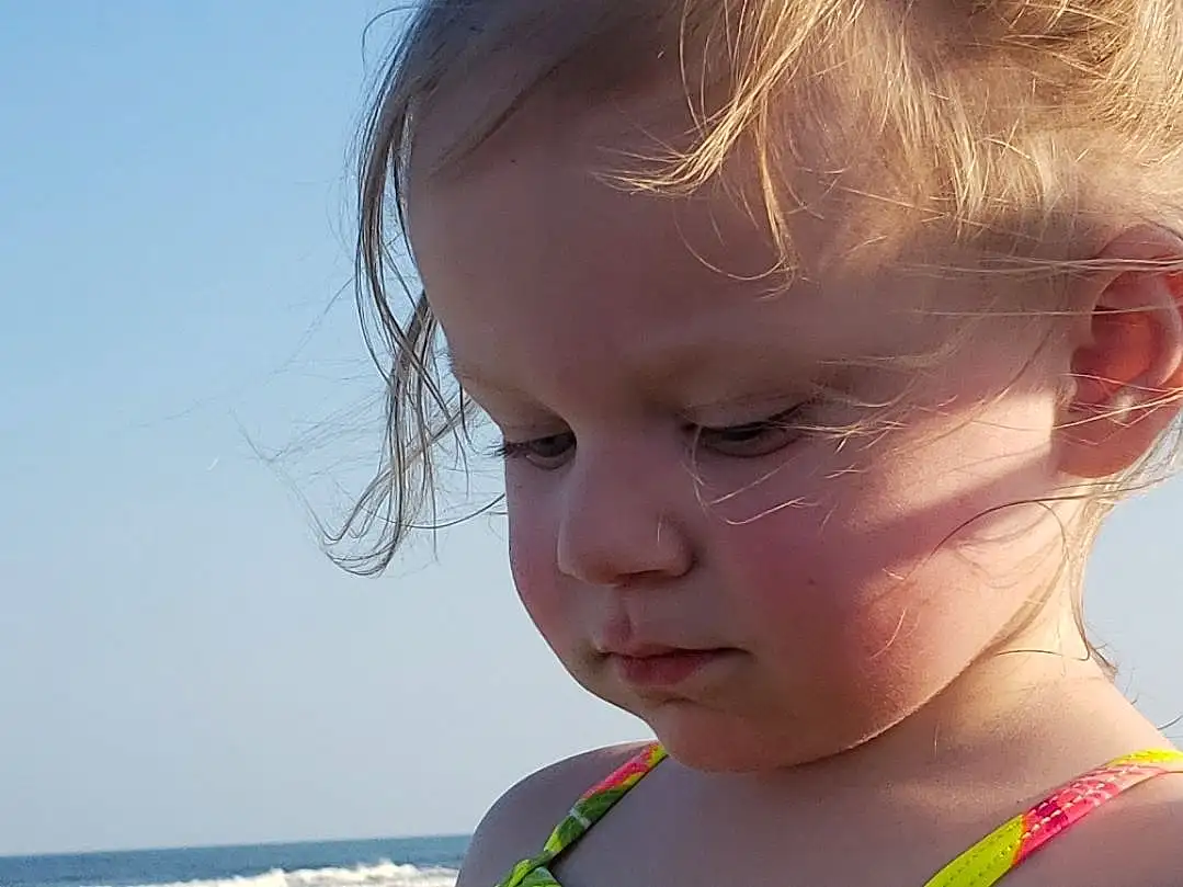 Nose, Face, Skin, Head, Lip, Chin, Sky, Shoulder, Eyes, Facial Expression, Water, Neck, Beach, Happy, Body Of Water, Sunlight, Fun, Baby & Toddler Clothing, Toddler, Summer, Person
