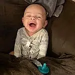 Nose, Cheek, Skin, Smile, Mouth, Comfort, Flash Photography, Sleeve, Baby & Toddler Clothing, Iris, Toddler, Happy, Baby, Linens, Sitting, Child, Fun, Room, Laugh, Portrait Photography, Person