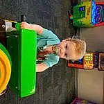 Photograph, Green, Standing, Leisure, Fun, Toddler, Gas, Recreation, Child, Human Settlement, Toy, Baby, Play, Machine, T-shirt, Plastic, Baby & Toddler Clothing, Room, Automotive Wheel System, Person