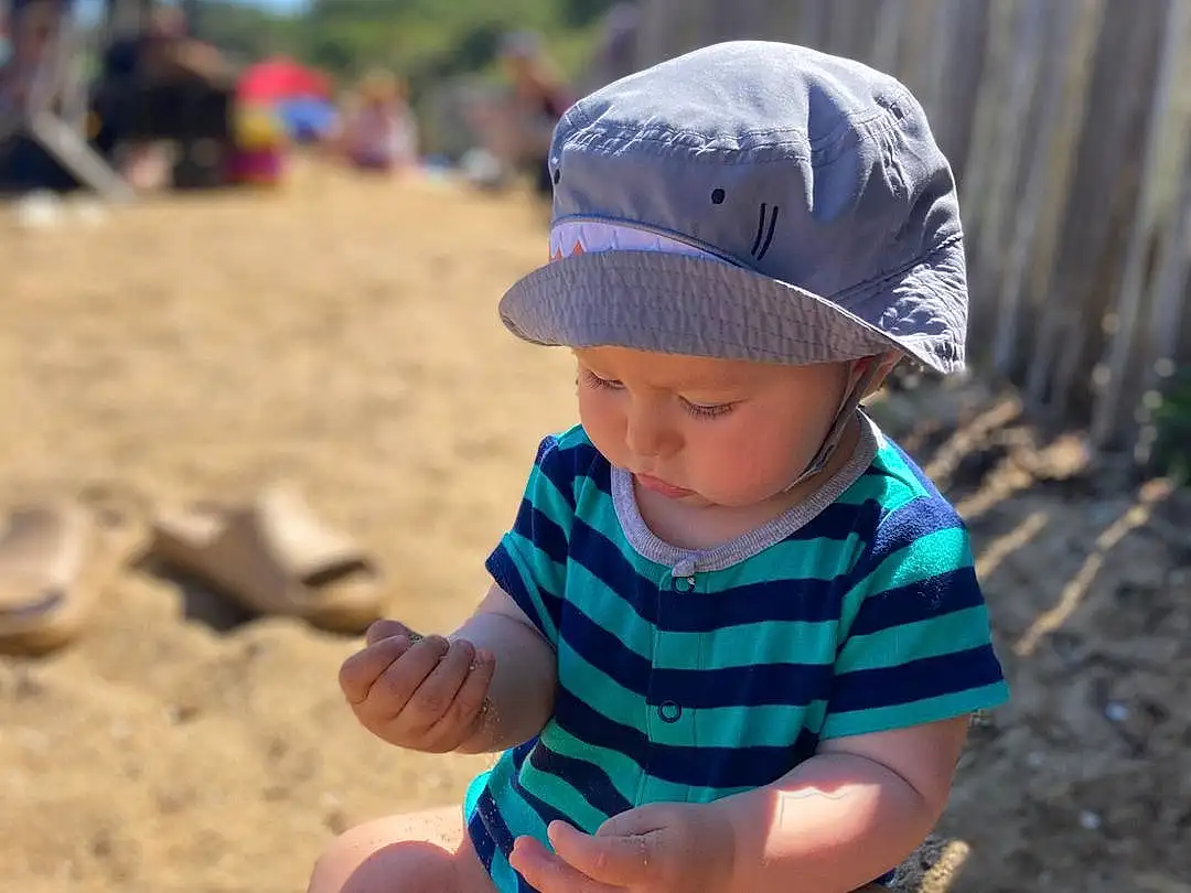 Clothing, Leg, People In Nature, Hat, Tree, Baby & Toddler Clothing, Sky, Cap, Toddler, Summer, Grass, People, Beach, Happy, Sand, Leisure, Shorts, Fun, Child, Sitting, Person, Headwear