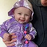 Clothing, Cheek, Skin, Outerwear, Smile, Purple, Sleeve, Cap, Baby & Toddler Clothing, Pink, Violet, Toddler, Happy, Baby, Child, Chair, Magenta, Electric Blue, Person, Joy, Headwear