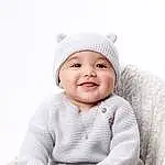 Smile, Skin, Outerwear, Photograph, Sleeve, Cap, Baby & Toddler Clothing, Happy, Comfort, Baby, Flash Photography, Headgear, Toddler, Child, Sitting, Pattern, Laugh, Portrait Photography, Fashion Accessory, Beanie, Person, Joy, Headwear