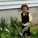 Plant, Smile, Flower, People In Nature, Leg, Grass, Happy, Terrestrial Plant, Groundcover, Lawn, Shrub, Toddler, Lawn Ornament, Garden, Leisure, Sitting, Gardening, Landscaping, Soil, Person, Joy