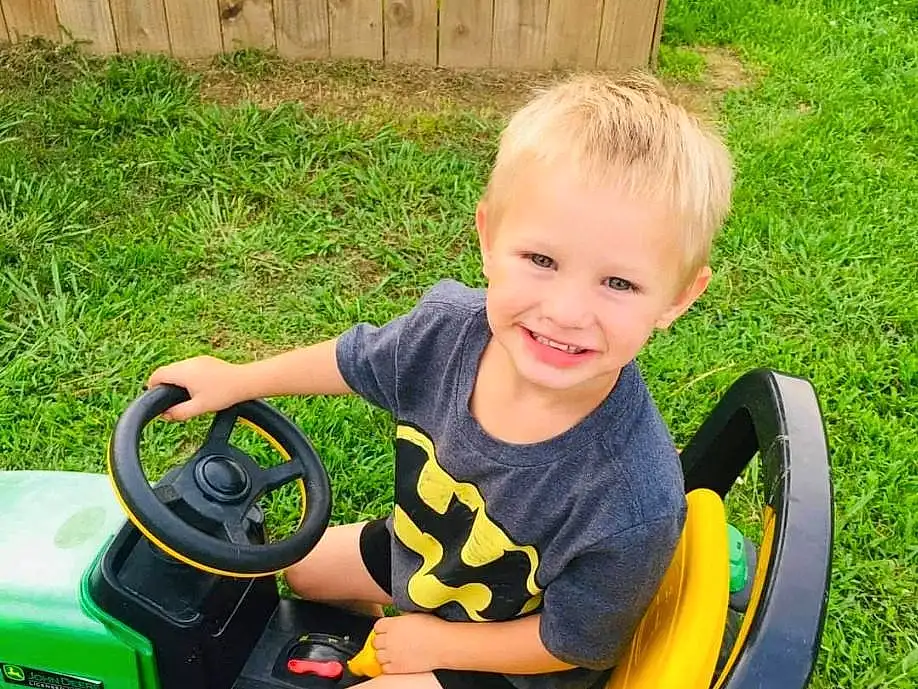 Wheel, Smile, Tire, Toy, Riding Toy, Automotive Tire, Vehicle, Grass, Shorts, Toddler, T-shirt, Leisure, Child, Lawn, Vroom Vroom, Automotive Design, Plant, Recreation, Happy, Fun, Person, Joy