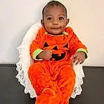 Face, Smile, Eyes, Dress, Baby & Toddler Clothing, Human Body, Orange, Sleeve, Baby, Happy, T-shirt, Toddler, Plant, Pumpkin, Peach, Personal Protective Equipment, Sitting, Workwear, Child, Person, Joy