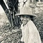 Smile, Hat, Plant, People In Nature, Sun Hat, Happy, Standing, Wood, Flash Photography, Black-and-white, Style, Headgear, Woody Plant, Grass, Adaptation, Child, Toddler, Tree, Monochrome, Black & White, Person, Joy, Headwear