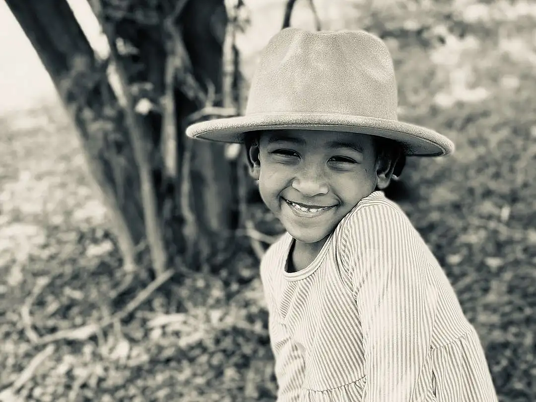 Smile, Hat, Plant, People In Nature, Sun Hat, Happy, Standing, Wood, Flash Photography, Black-and-white, Style, Headgear, Woody Plant, Grass, Adaptation, Child, Toddler, Tree, Monochrome, Black & White, Person, Joy, Headwear